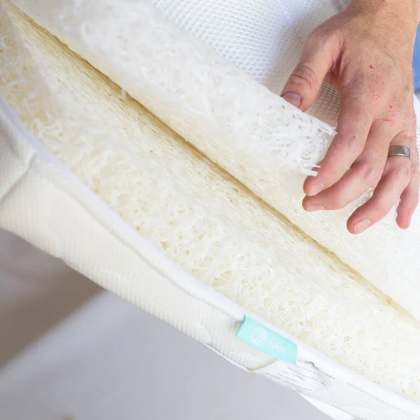 Person holding a rolled-up mattress topper with a close-up view