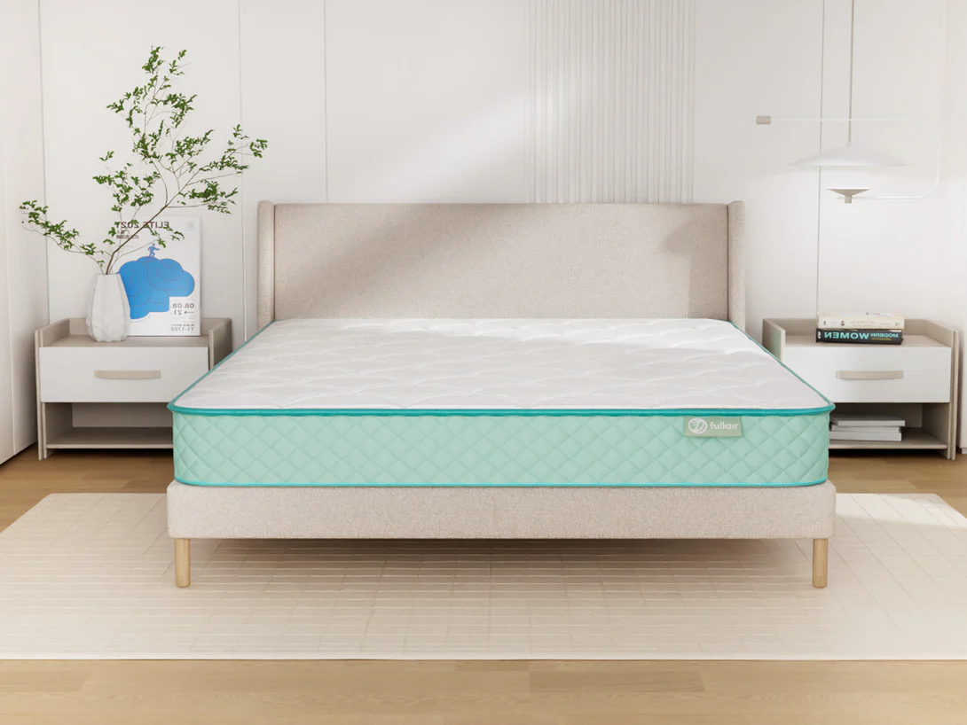 Mattress on a bed frame in a bedroom setting with a plant and nightstands.