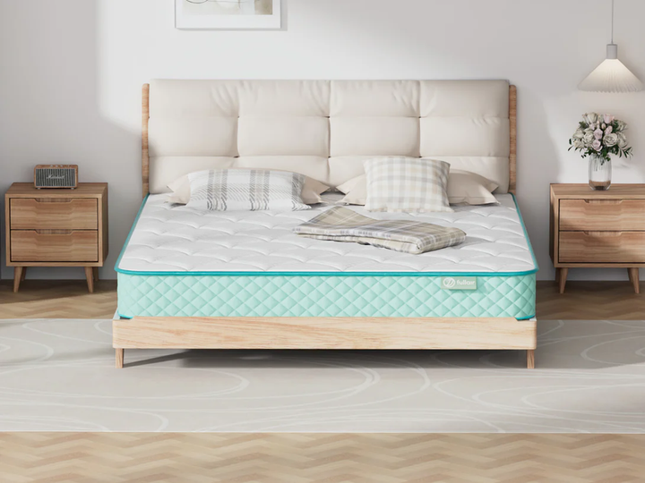 Mattress on a bed with wooden frame and side tables in a room setting